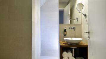 A modern bathroom with a large white sink, a mirror, and a towel rack.