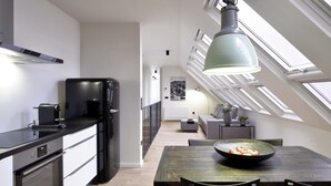 A modern kitchen with a dining area, skylight, and a view of the living room. - Hotel Maribor, City apartments (Maribor)