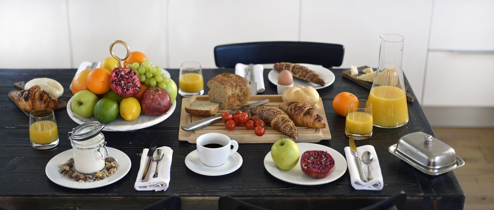 Ein Frühstückstisch mit verschiedenen Speisen, darunter Obst, Brot und Getränke.
