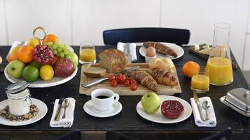 Ein Frühstückstisch mit verschiedenen Speisen, darunter Obst, Brot und Getränke.