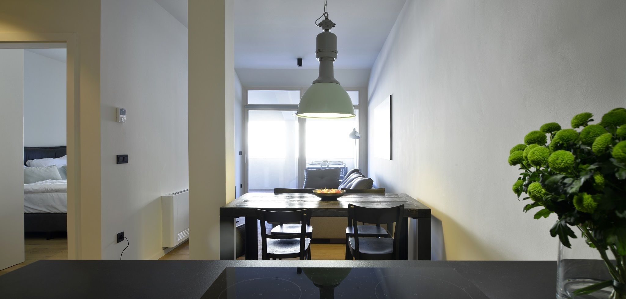 A modern dining area with a table, chairs, and a hanging light fixture.