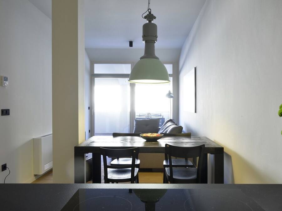 A modern dining area with a table, chairs, and a hanging light fixture.