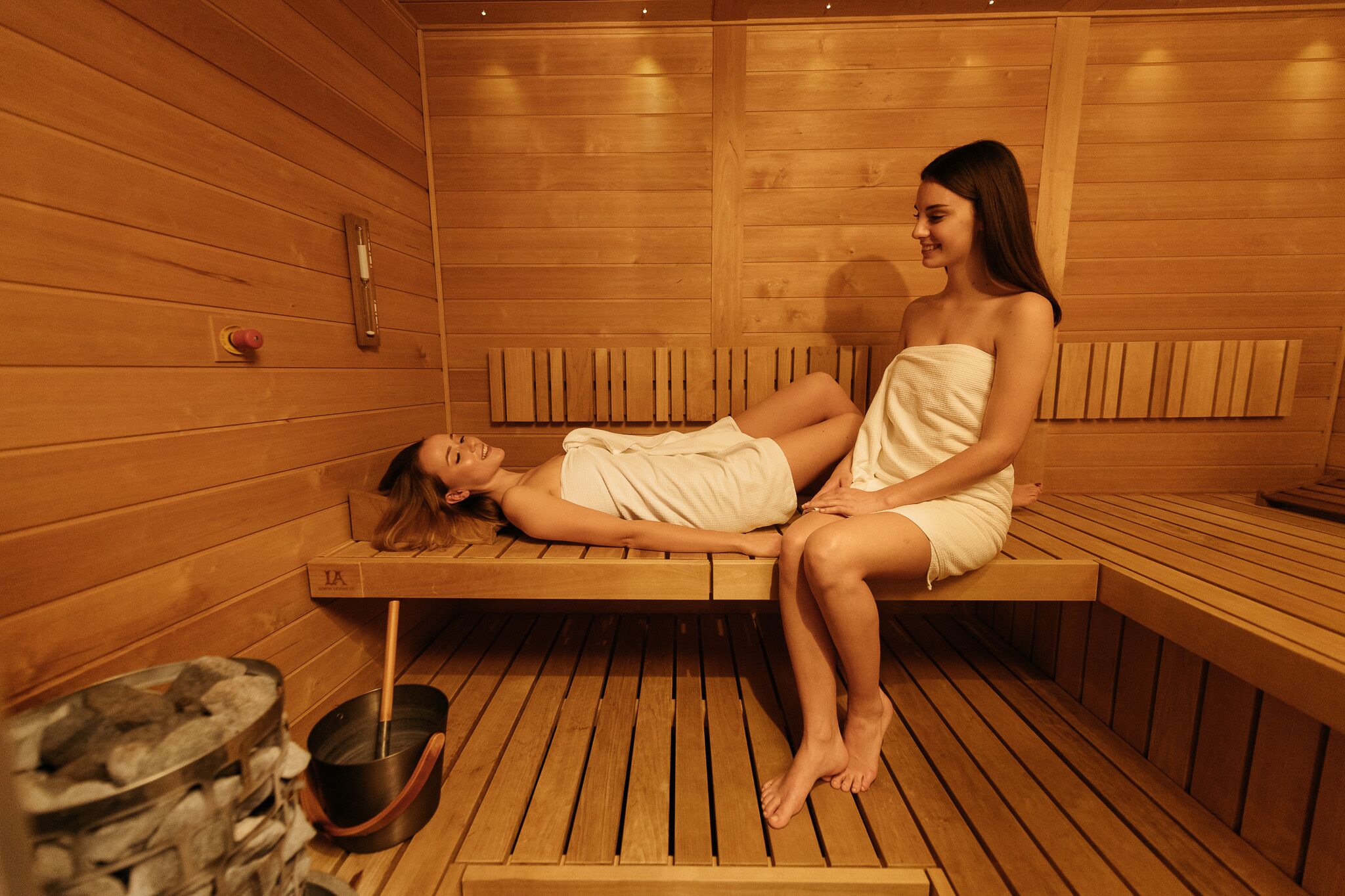 Una sauna con bancos de madera y una pileta de piedra.