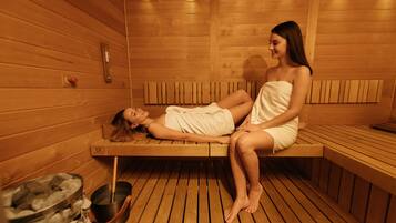 Una sauna con bancos de madera y una pileta de piedra.
