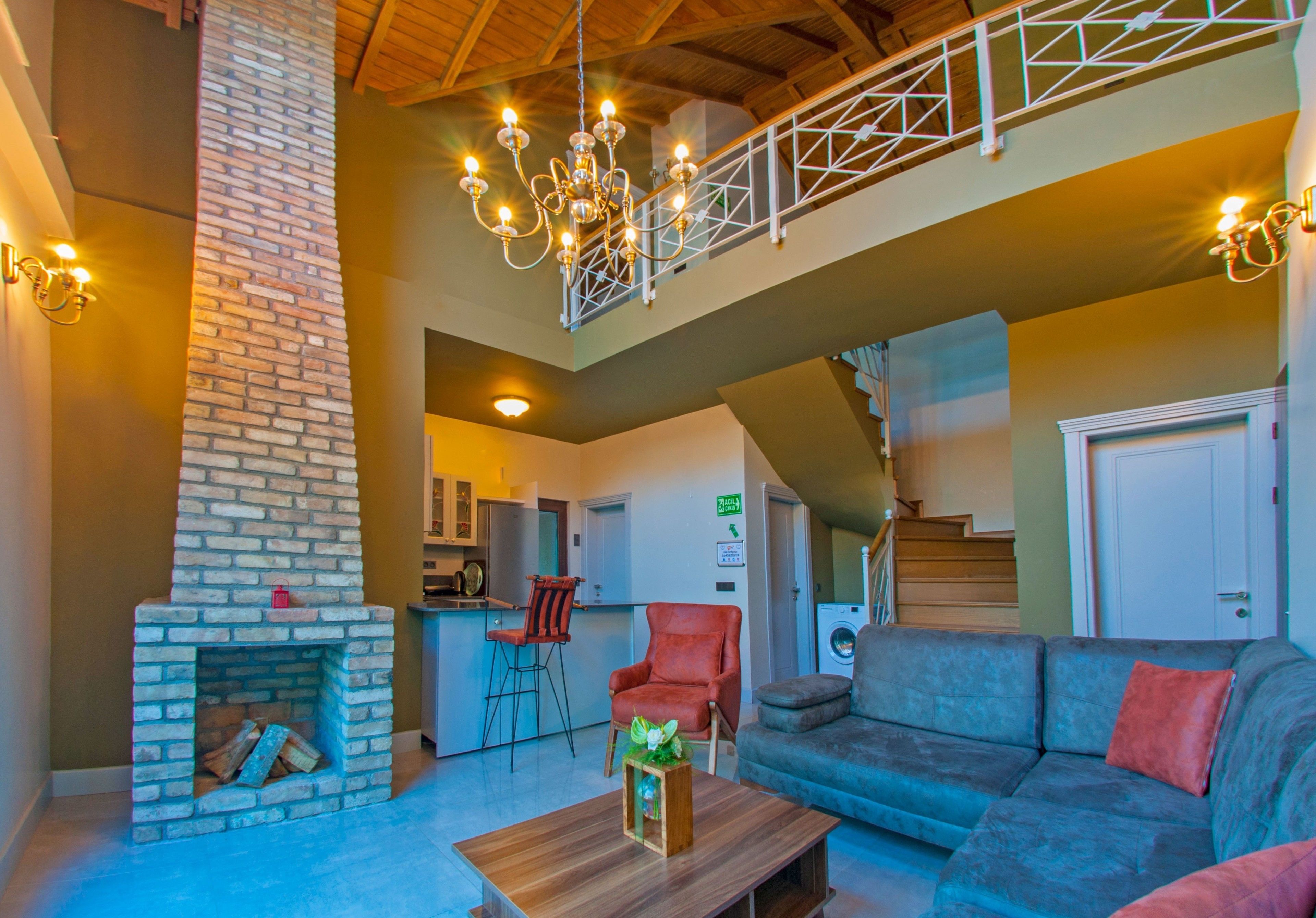 A spacious living area with a fireplace, a sofa, a coffee table, and a staircase leading to an upper level.