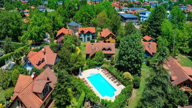 Un quartier résidentiel avec des maisons, une piscine et un lac en arrière-plan.