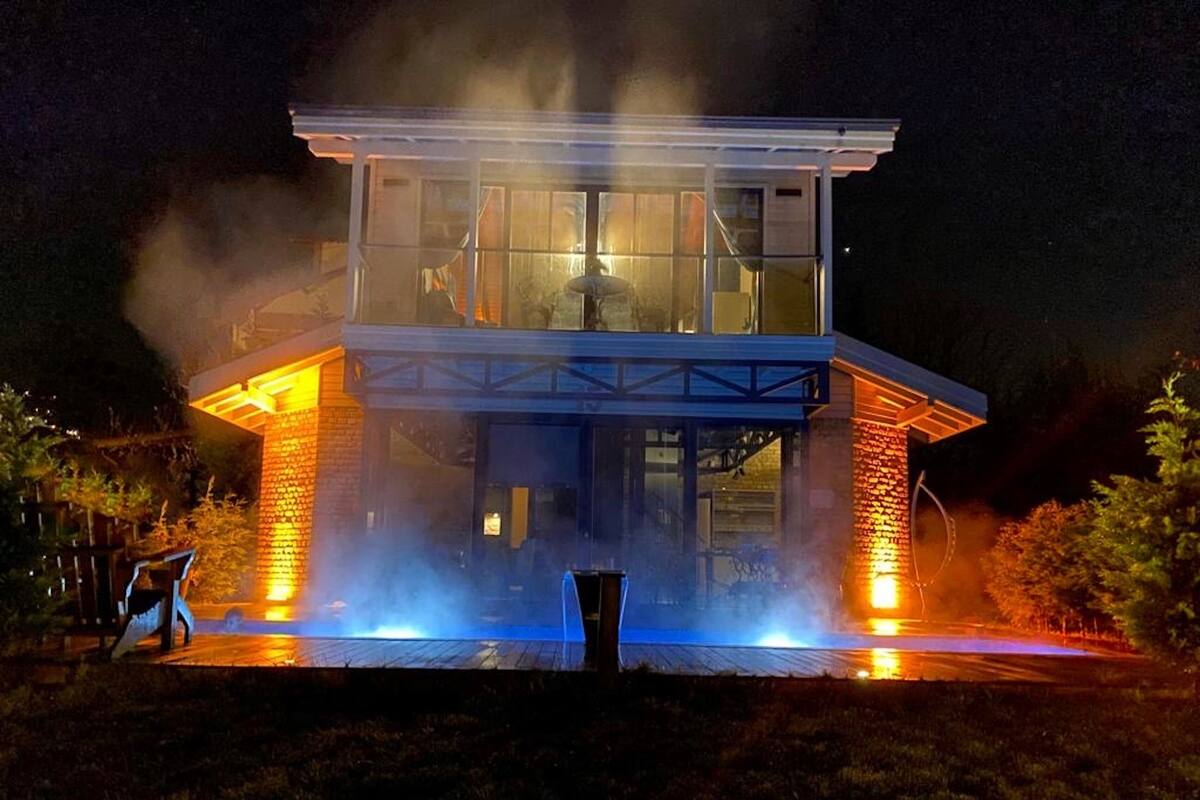 Een modern huis met twee verdiepingen, een glazen gevel, een bakstenen buitenkant en een zichtbare garage.
