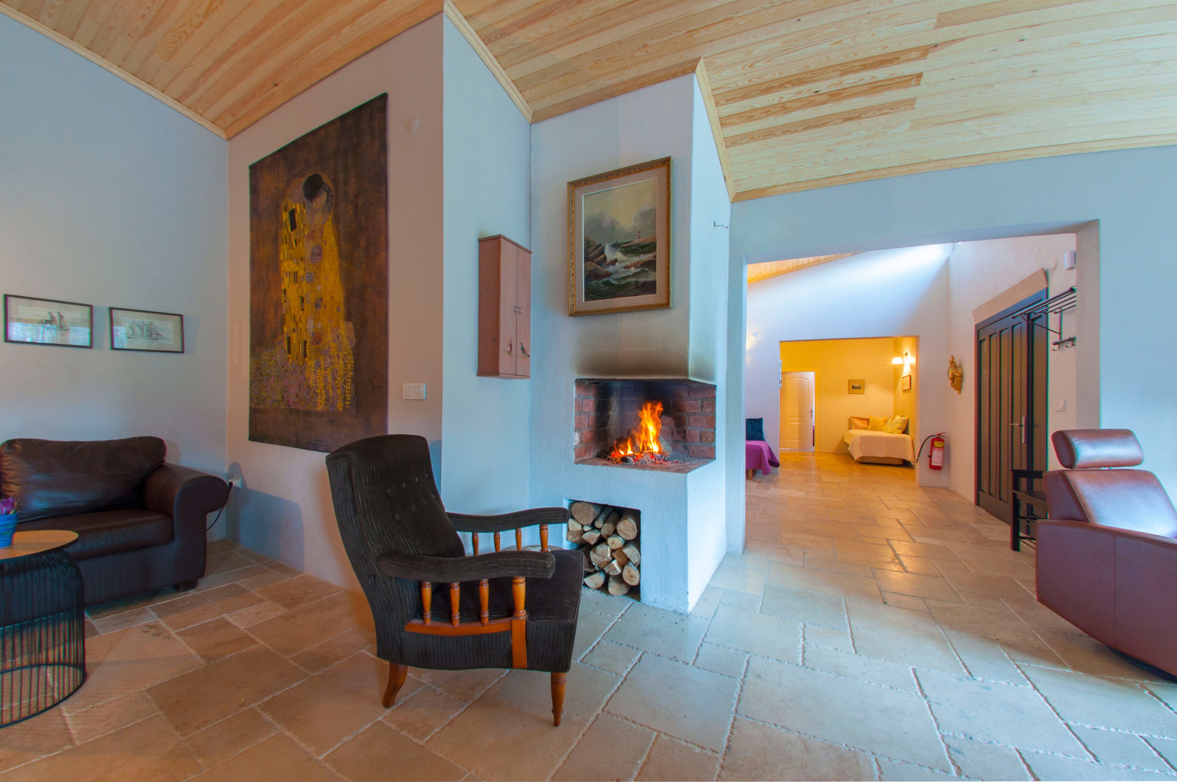 A living room with a fireplace, a sofa, a chair, and a painting on the wall.