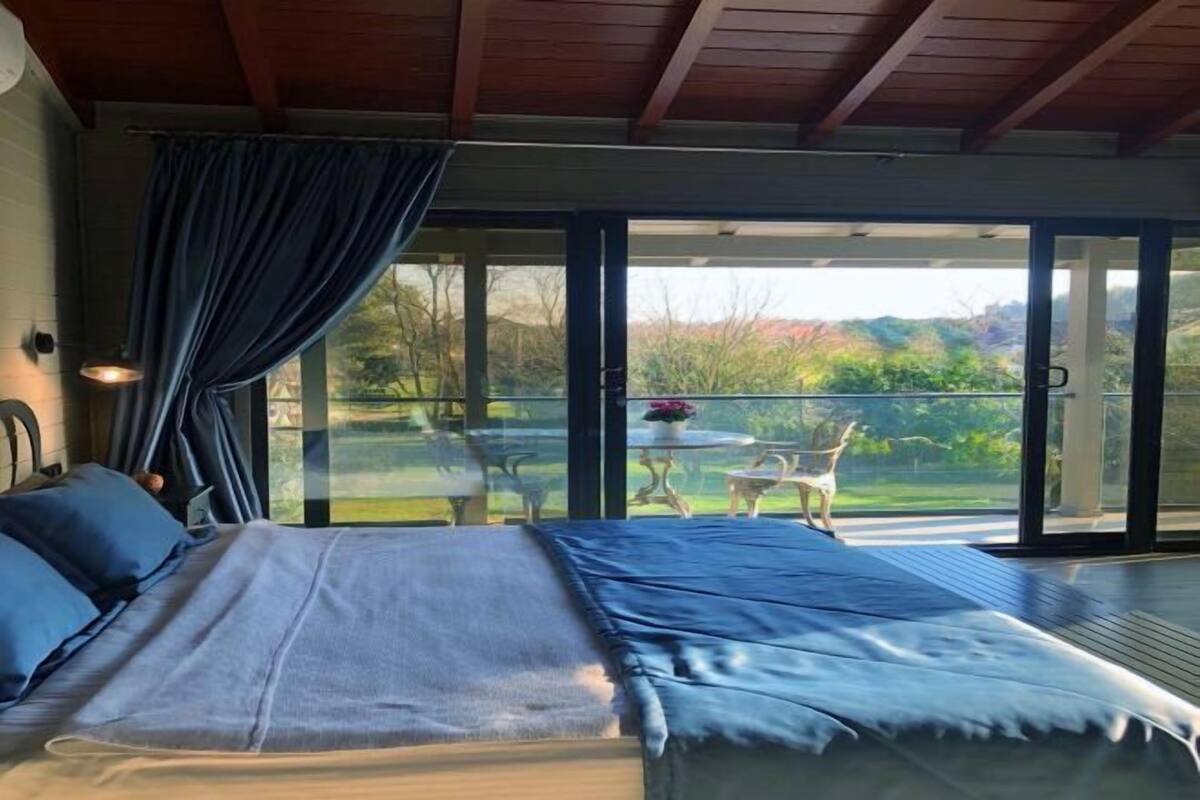 Een slaapkamer met een bed, een raam en uitzicht op de omgeving.