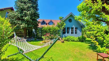 Relax in a serene garden with a hammock, surrounded by lush plants and flowers.