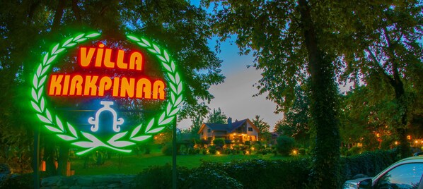 Letrero que dice 'Villa Kirkpinar', con una corona de laurel y un símbolo de nota musical.