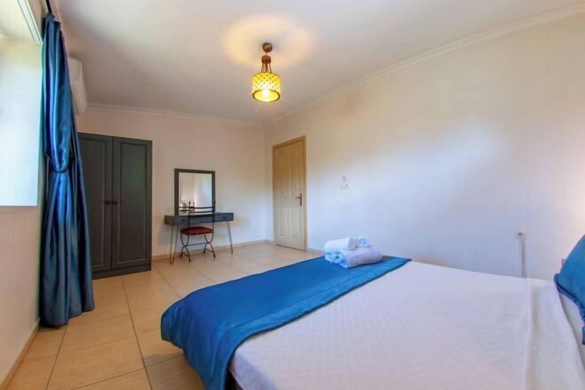 Een hotelkamer met een bed, een bureau, een stoel, een kledingkast en een deur.