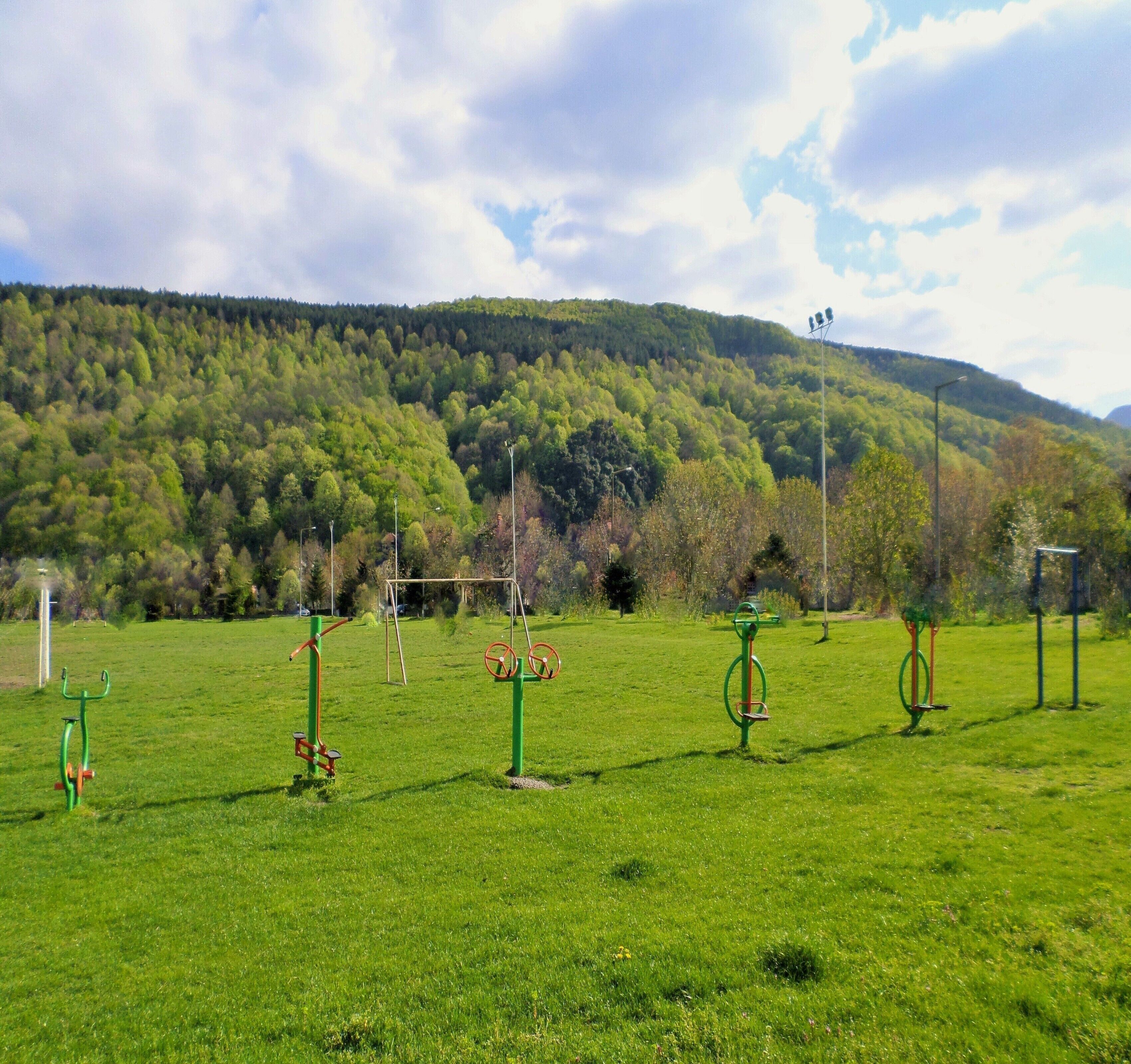 Eine Wiese mit Trainingsgeräten und einem bewaldeten Hügel im Hintergrund.