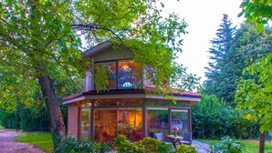 Une maison moderne dotée d’une façade en verre, d’un balcon et d’une terrasse en pierre.