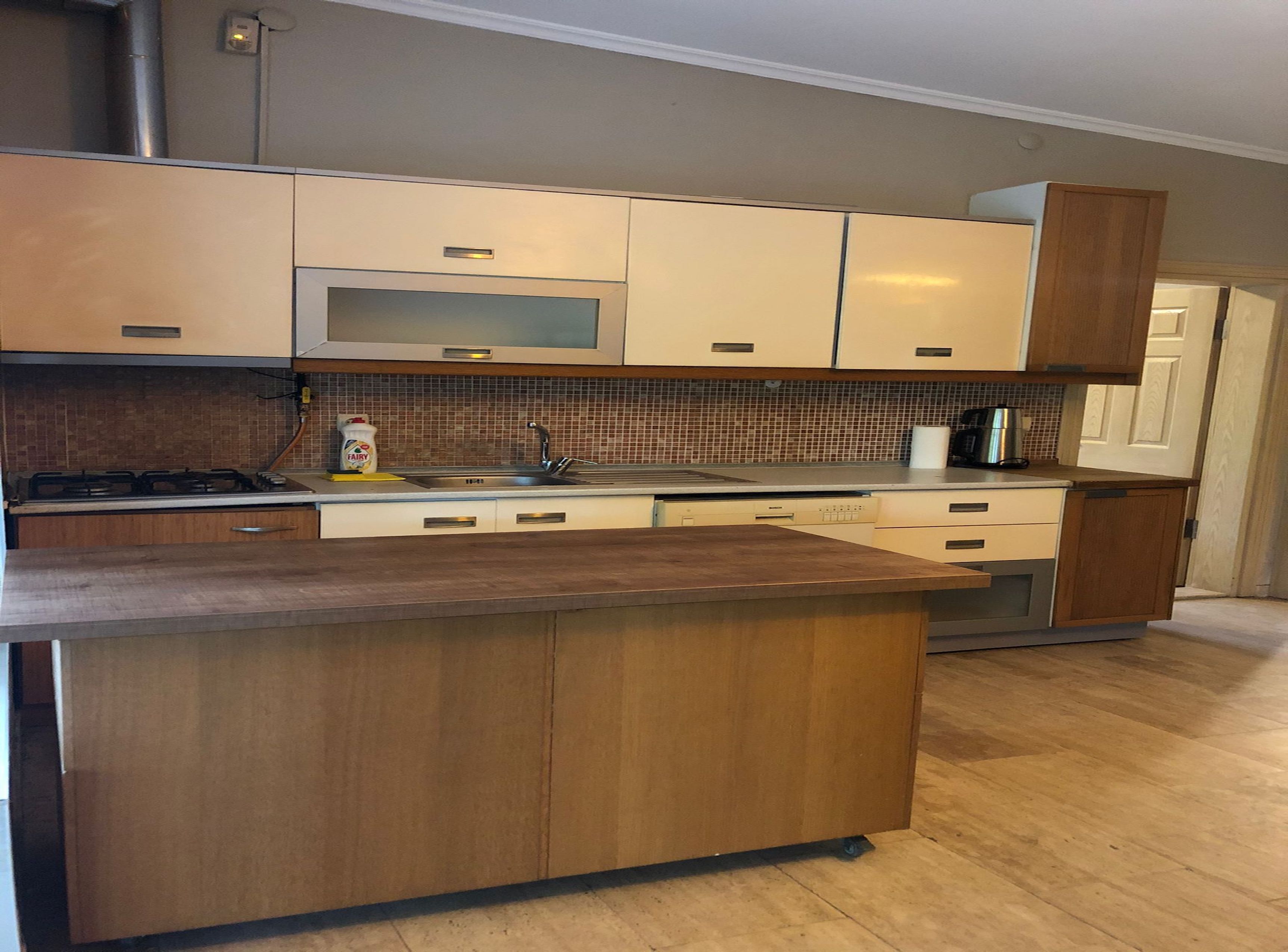 A modern kitchen with wooden cabinets, a stainless steel sink, and a microwave.