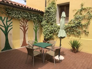 An outdoor patio with a table and chairs, a potted plant, and a wall with tree murals.