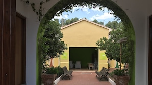An outdoor area with a yellow building, two benches, and potted plants.