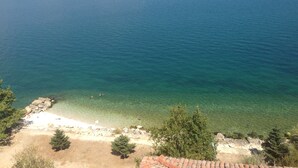 A coastal view with clear water, a sandy beach, and rocky outcrops. - Fulya Pension (Egirdir)