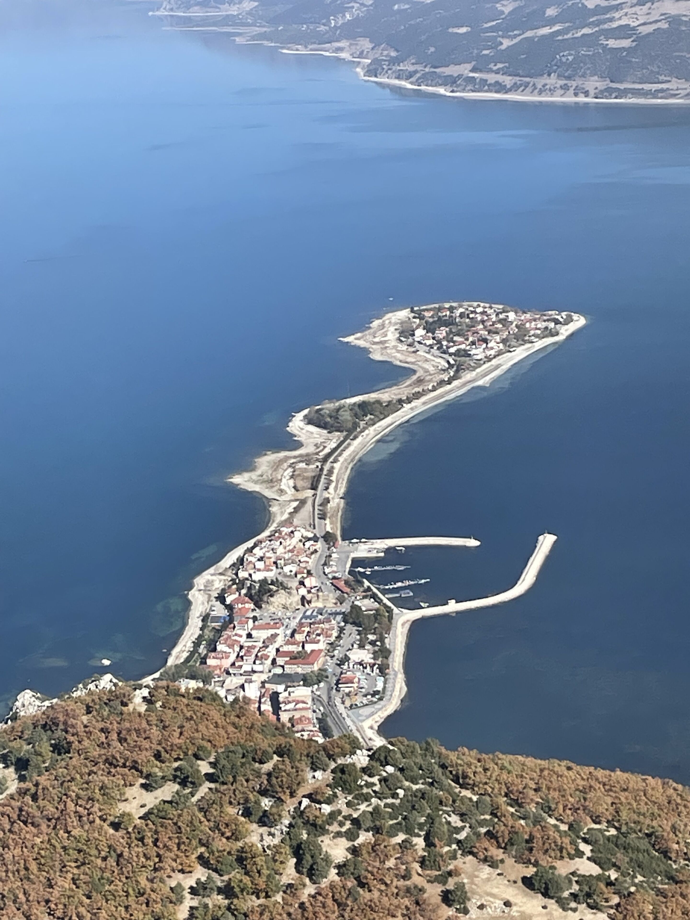 Ein Luftbild einer Küstenstadt mit einer langen Halbinsel, die durch eine Brücke mit dem Festland verbunden ist.