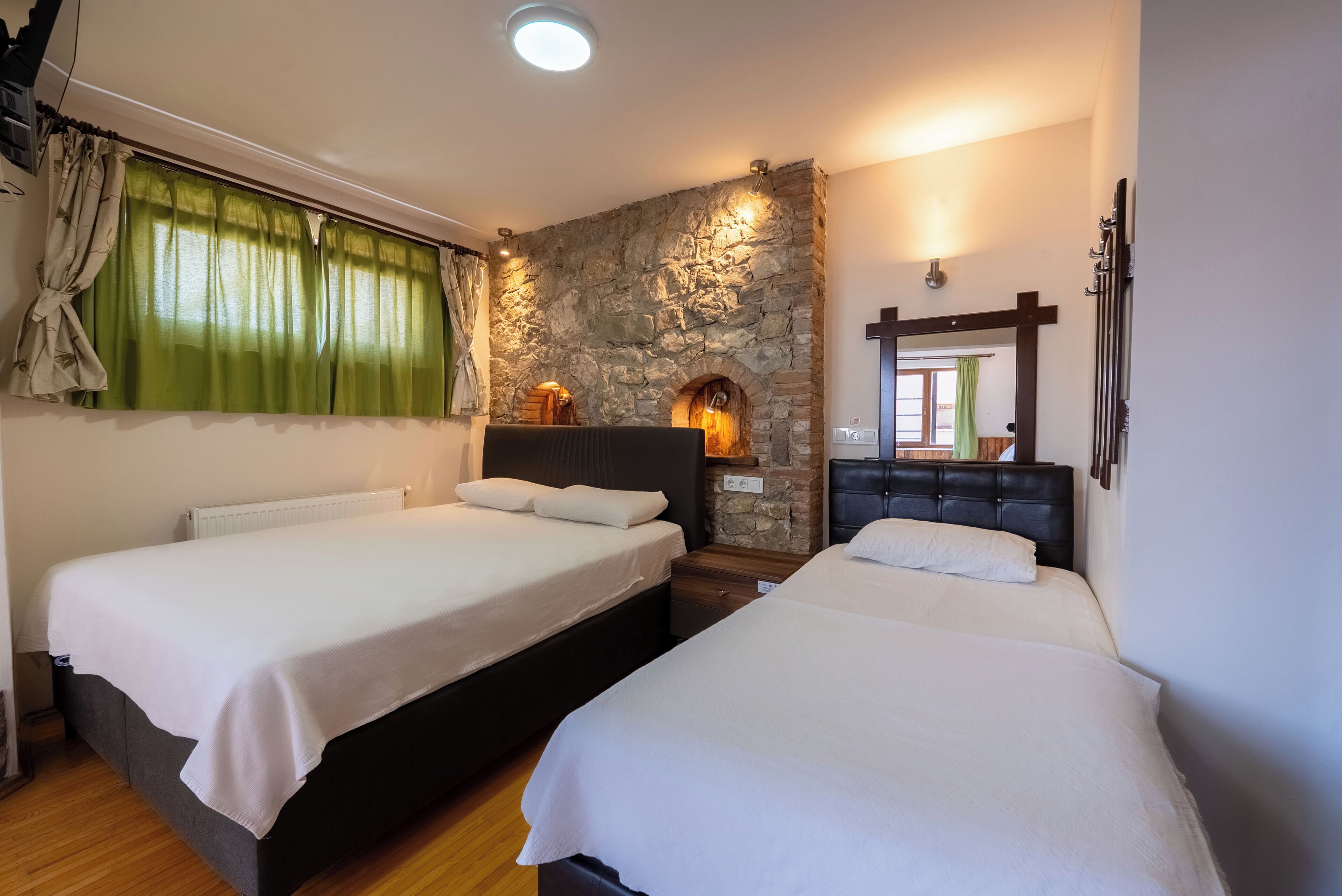 Une chambre avec deux lits, un mur en pierre et une cheminée.
