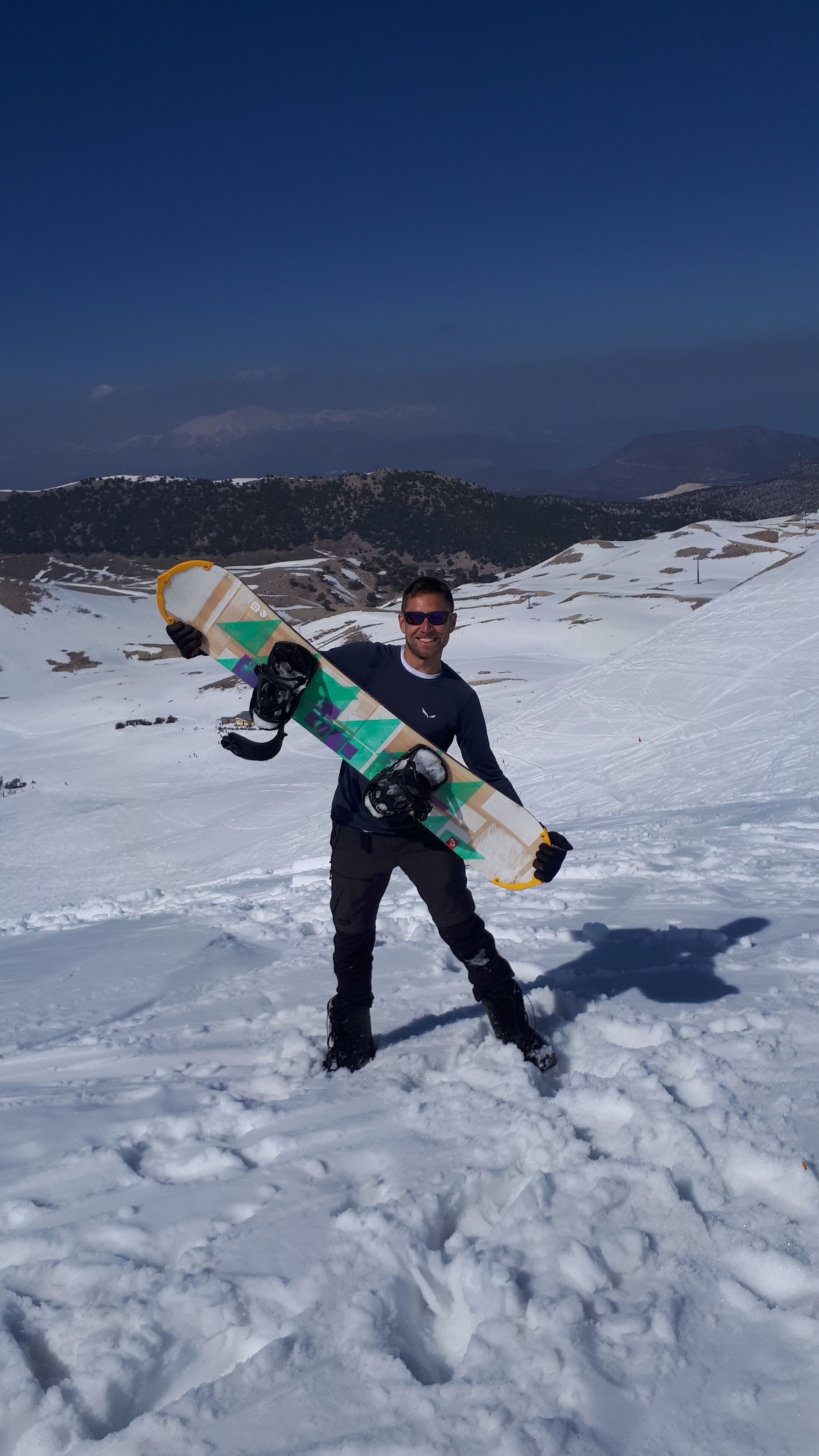 Una persona sosteniendo una tabla de snowboard en una montaña nevada.