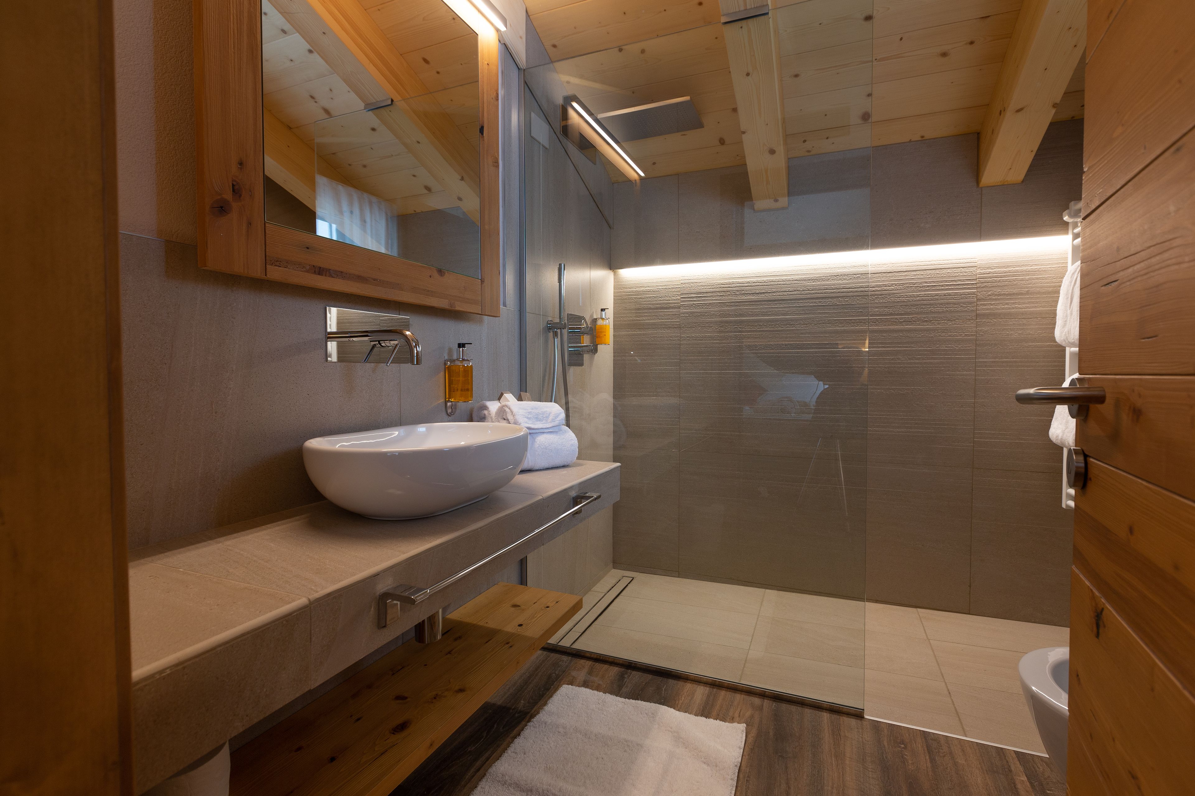 A modern bathroom with a large sink, mirror, and shower.