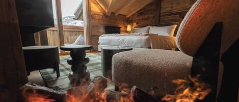 A cozy cabin interior with a fireplace, a sofa, a round table, and a bed.