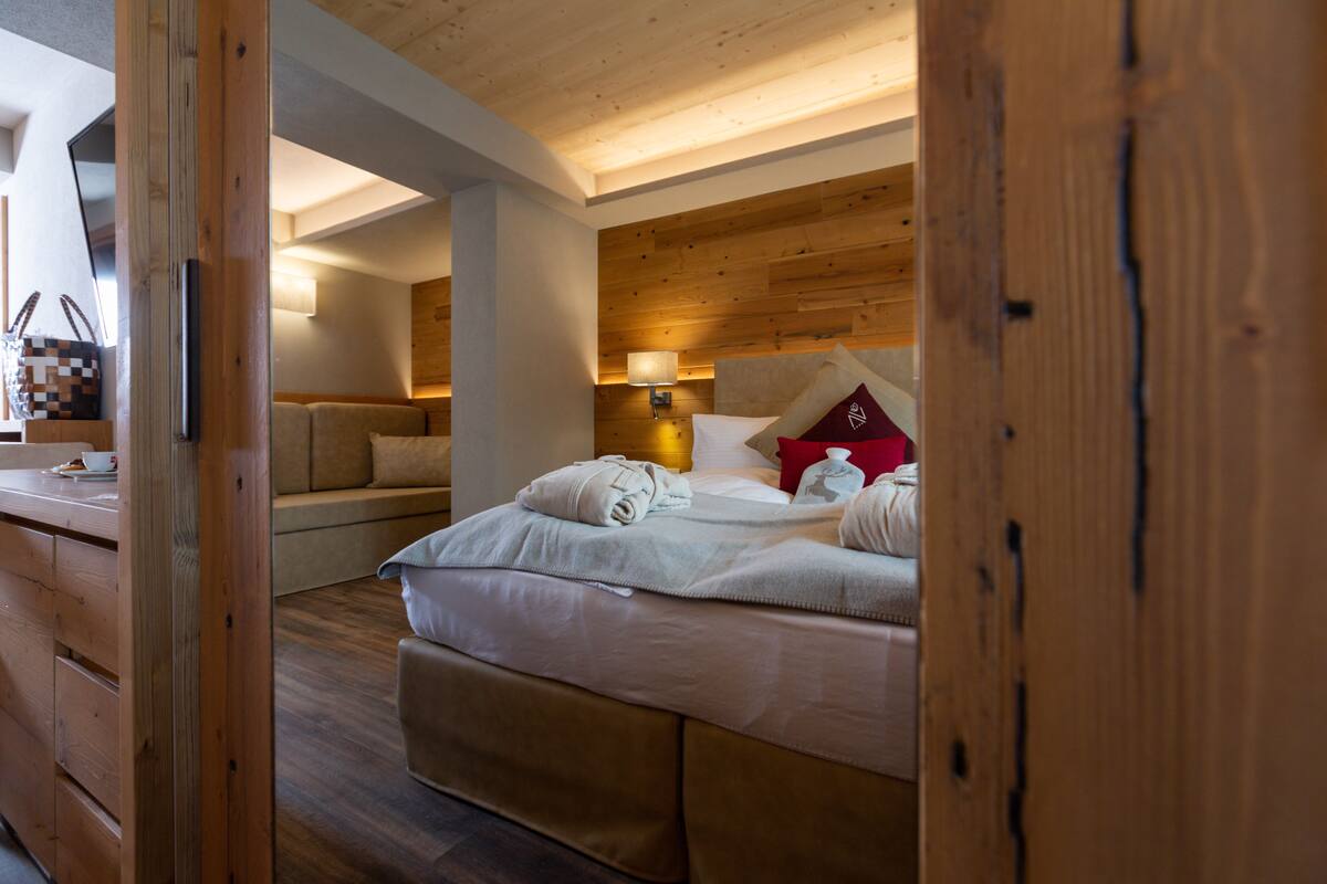 Una habitación con techo de madera, una cama con ropa blanca, una mesita de noche y una lámpara.