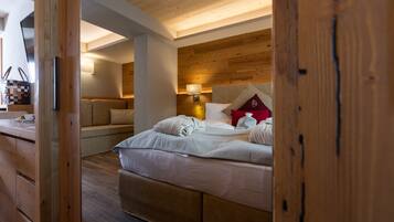 A room with a wooden ceiling, a bed with white bedding, a nightstand, and a lamp.