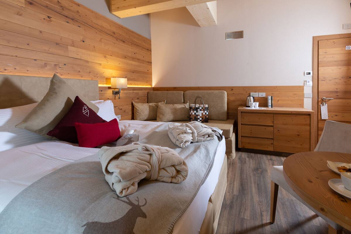 Una habitación con paneles de madera, una cama, una mesita de noche y una pequeña mesa de comedor.