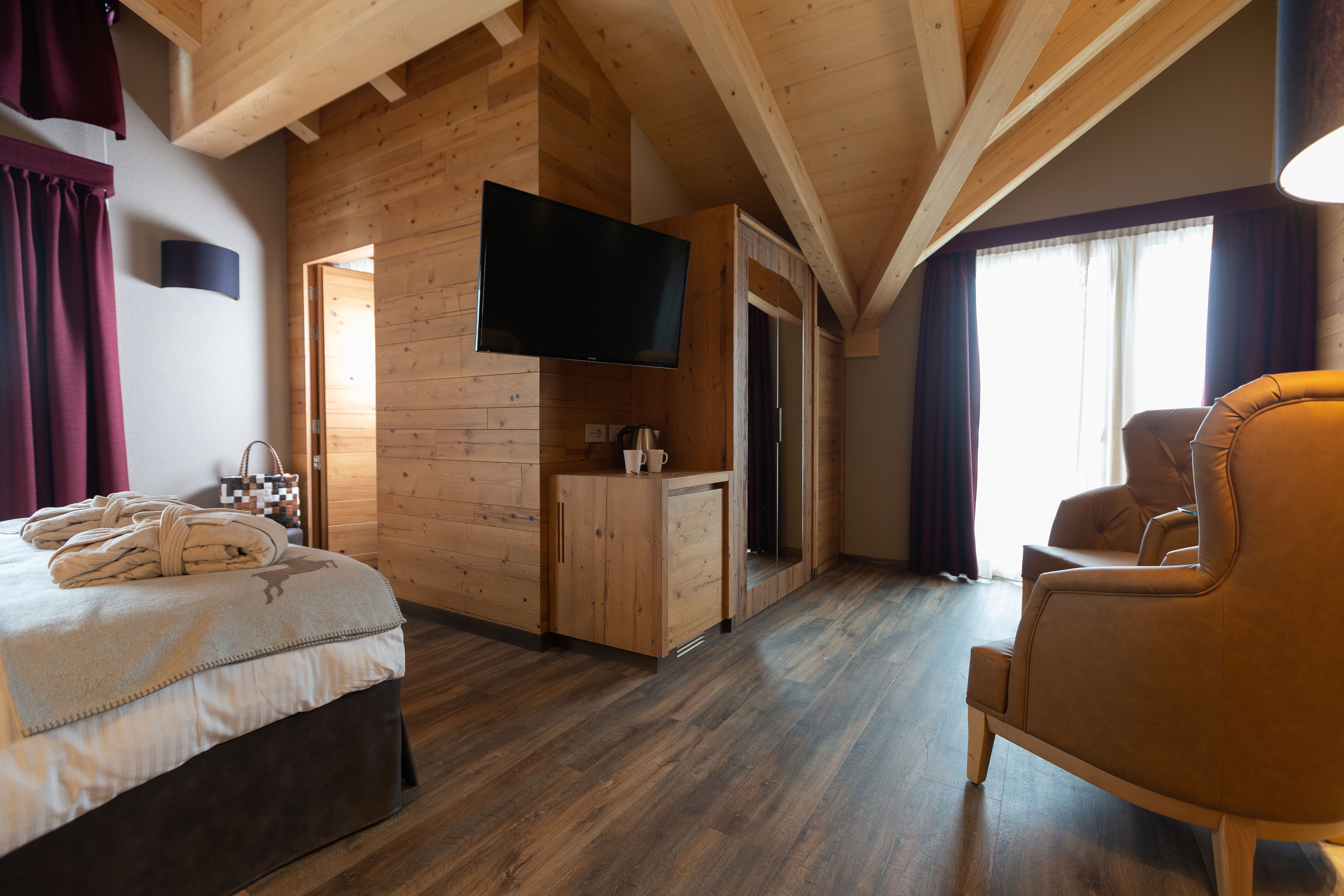 A room with a bed, a TV, a wooden cabinet, and a chair.