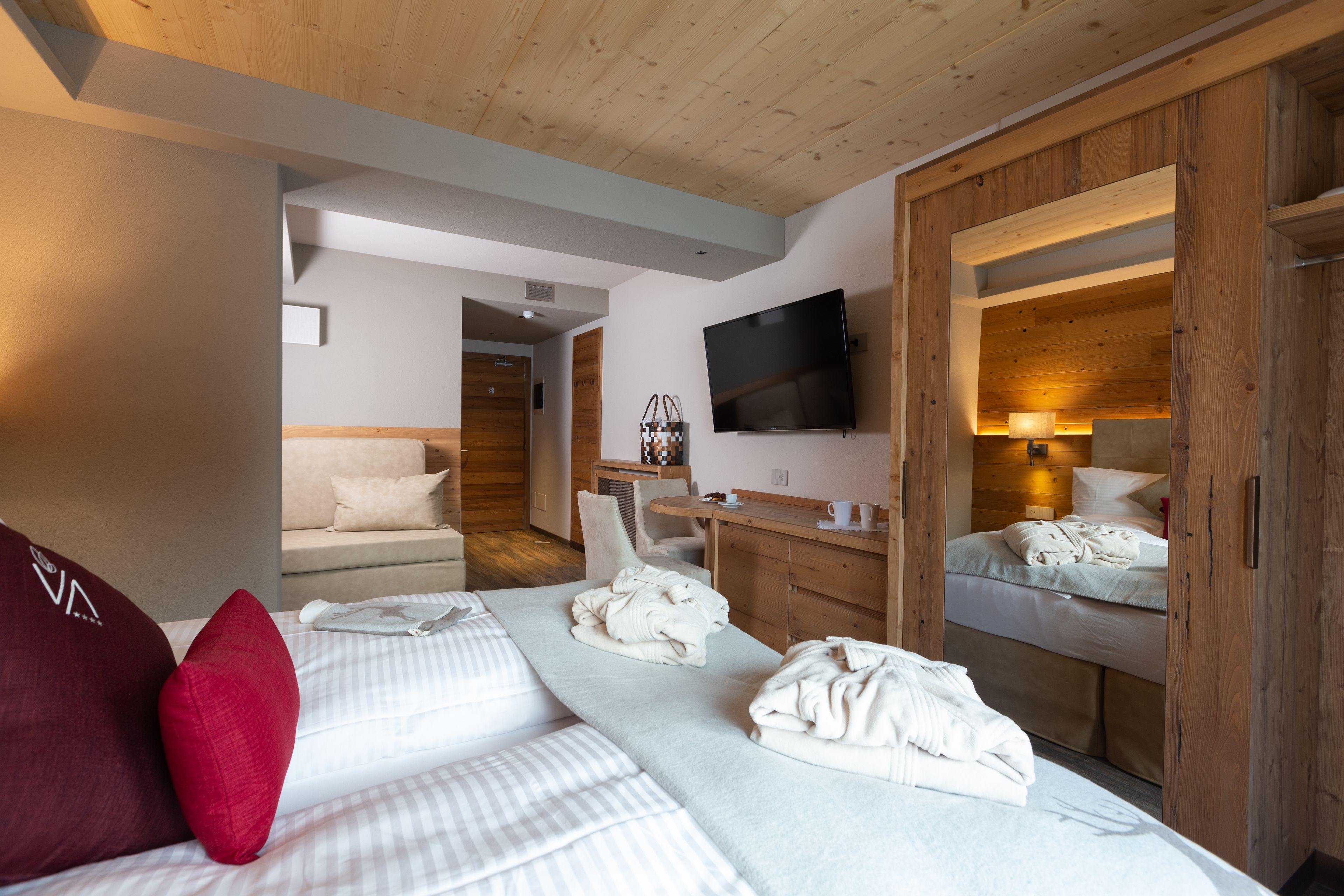 A modern hotel room with a large bed, a desk, and a TV.