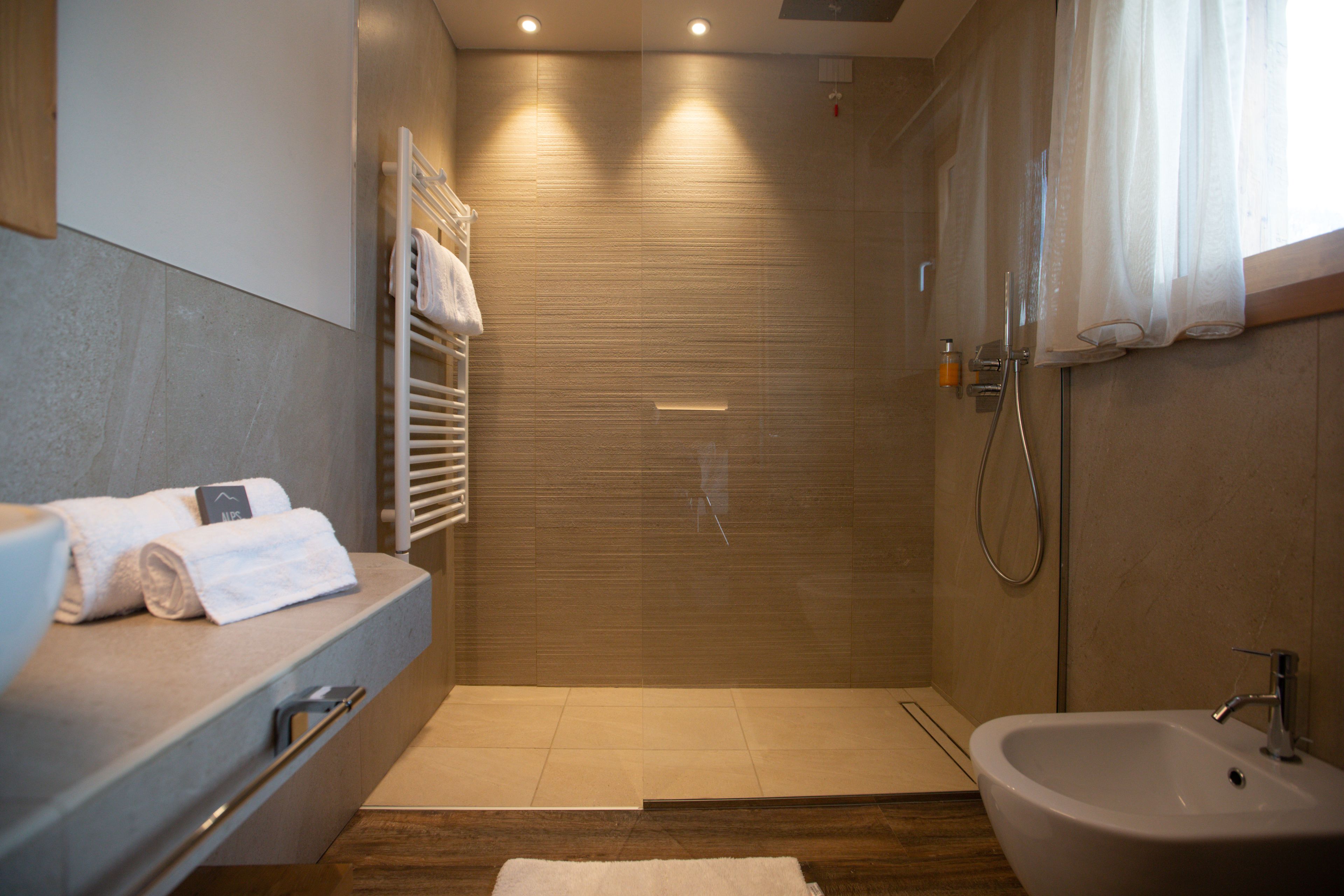 A modern bathroom with a shower, a sink, and a towel rack.