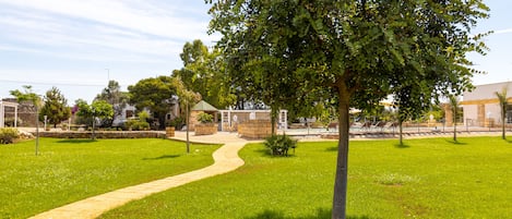 A grassy area with a paved path leading to a building with a stone facade.