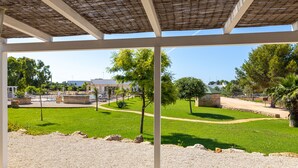 Un espacio al aire libre con una zona de estar cubierta, un césped y un sendero.