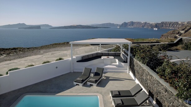 Terraço no telhado com piscina, espreguiçadeiras e vista para o mar e falésias.