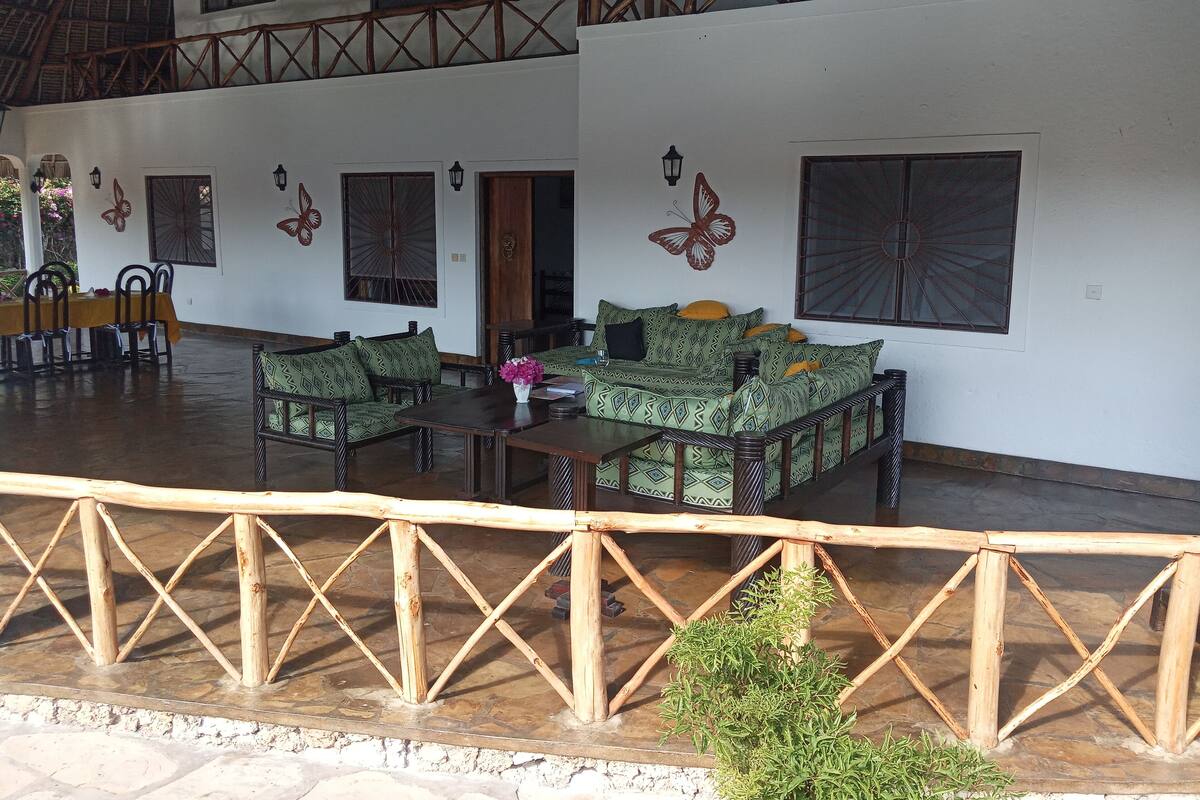 Un amplio espacio al aire libre con mobiliario de madera y una barandilla decorativa.
