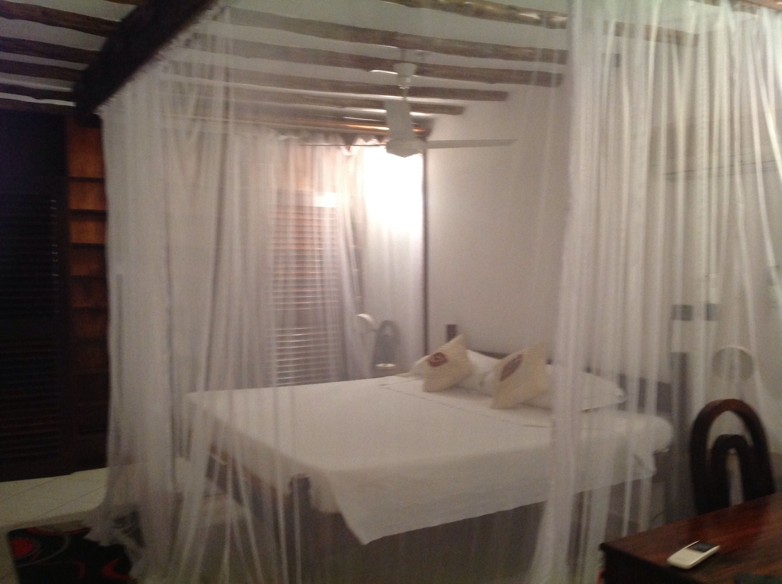 A bed with a canopy, a bedside table, and a chair.
