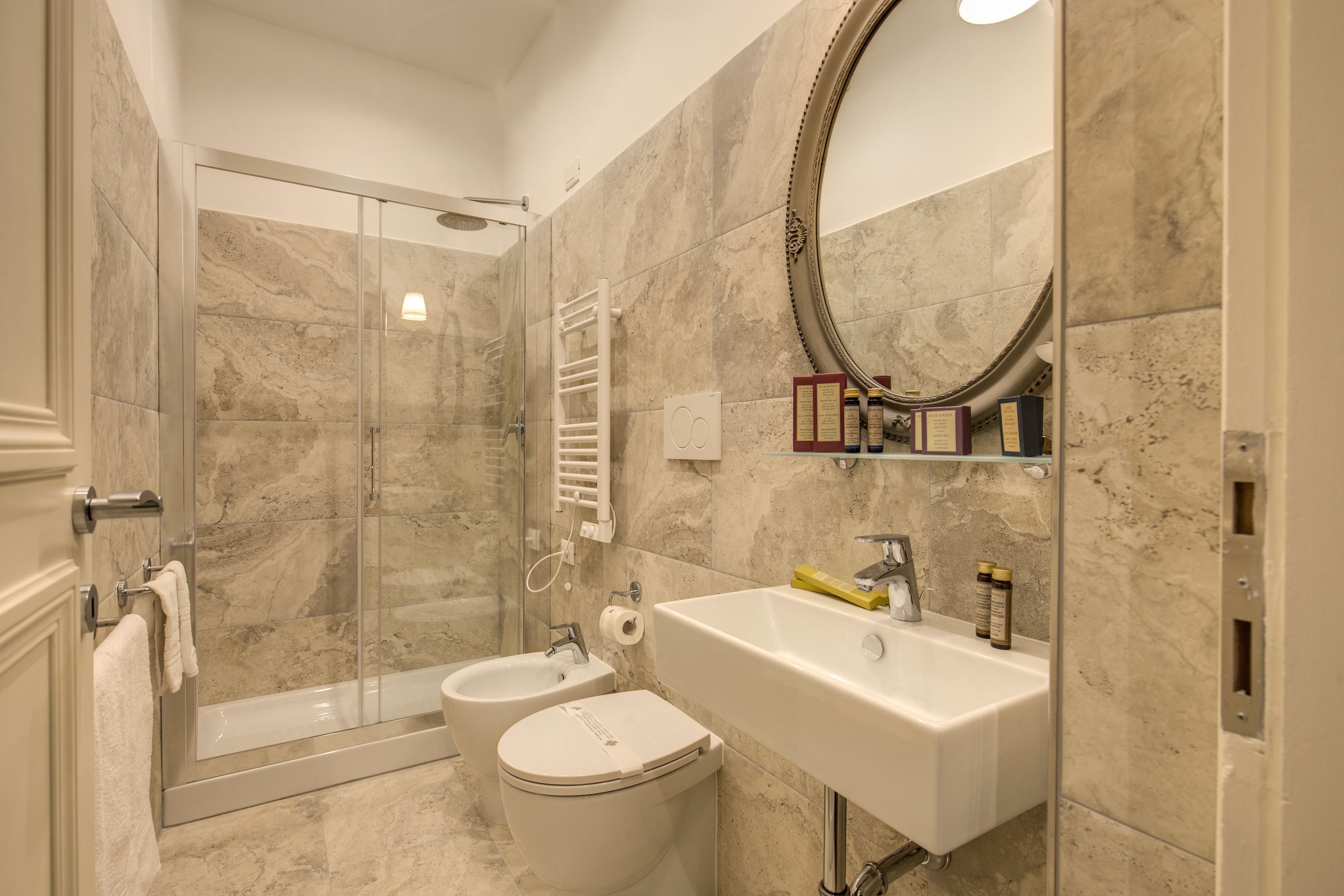 Un baño moderno con ducha de vidrio, lavamanos blanco y retrete.