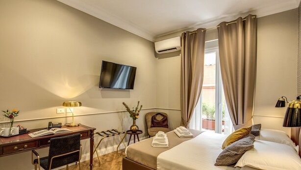 Een hotelkamer met een bed, bureau, stoel, televisie en een raam met gordijnen.