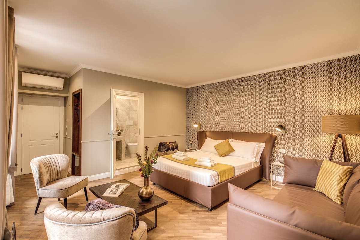 Une chambre d’hôtel moderne avec un grand lit, un canapé, un fauteuil et une petite table.