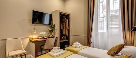 A hotel room with two beds, a desk with a chair, a TV, and a wardrobe.