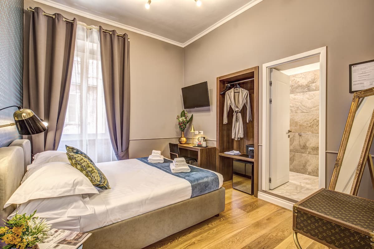 Une chambre d’hôtel équipée d’un lit, d’un bureau, d’une télévision, d’une douche et d’un miroir.