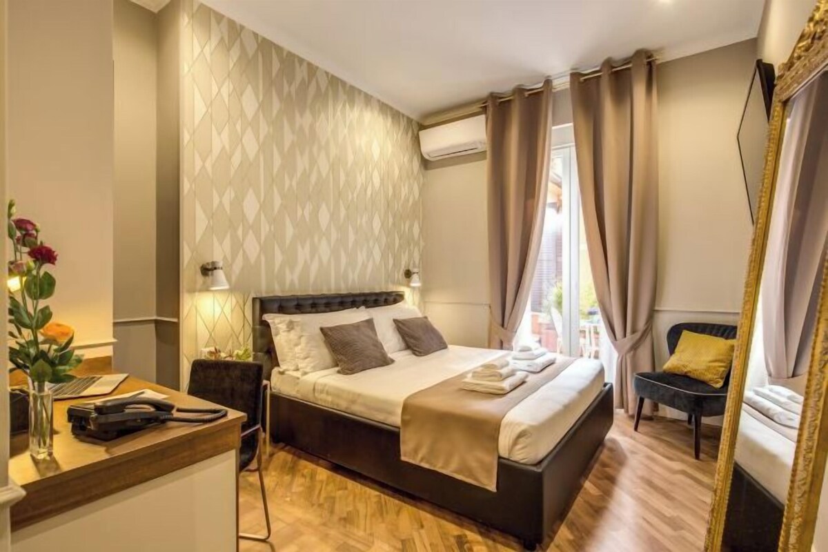Un dormitorio con cama, mesita de noche, lámpara y espejo.