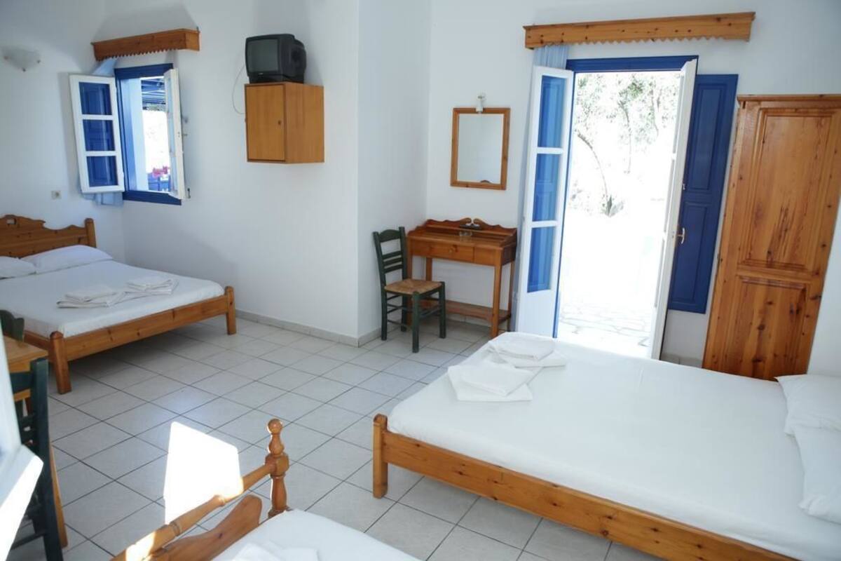 Un dormitorio con dos camas de madera, un escritorio, una silla, un espejo y un armario.