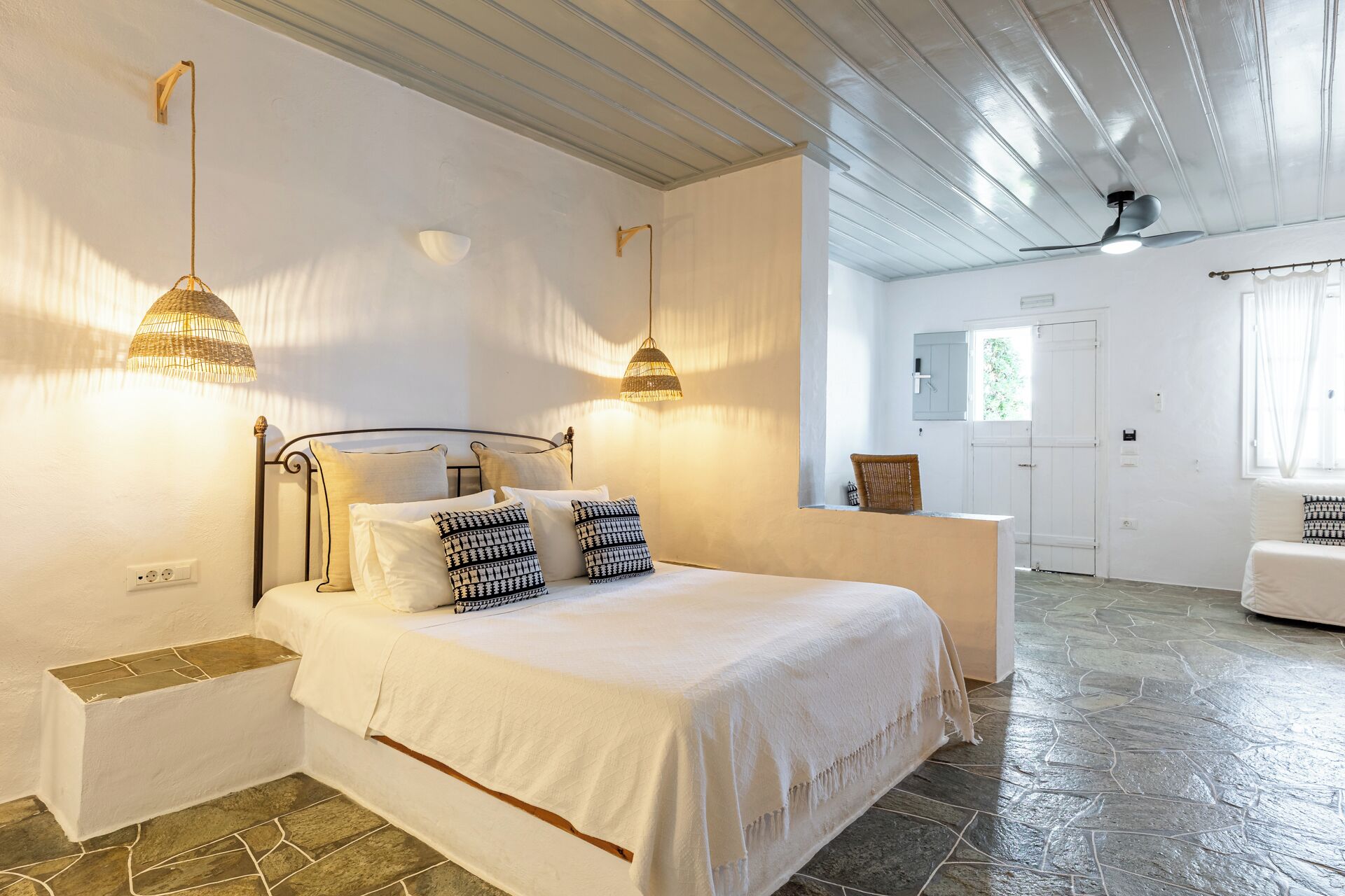 Un dormitorio con una cama, dos lámparas de pared, una ventana y una puerta.