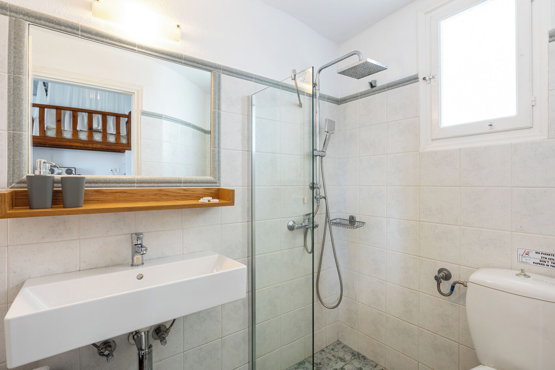 Une salle de bain avec un lavabo blanc, une cabine de douche en verre et des toilettes.