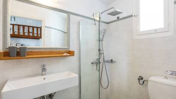 Une salle de bain avec un lavabo blanc, une cabine de douche en verre et des toilettes.
