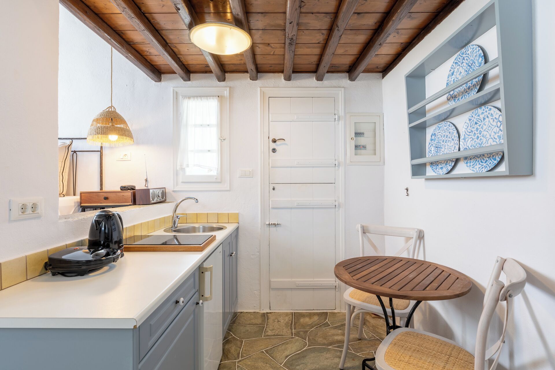 A compact kitchen with a built-in stove, a sink, and a small dining area with a table and two chairs.