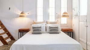 Une chambre à coucher avec un lit, deux tables de chevet, une échelle en bois et une armoire.